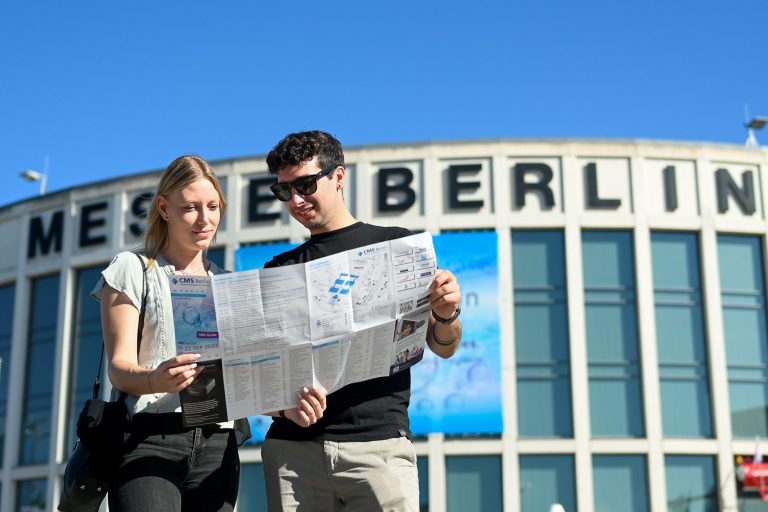 Ein Paar steht vor der Messe Berlin und schaut auf eine Karte.